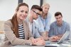 Vier Personen sitzen am Schreibtisch und arbeiten zusammen am Laptop. 